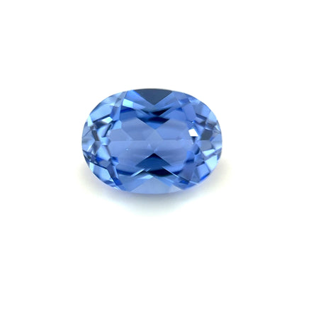 An 8x6 Exceptional Oval Lab Created Light Blue Sapphire is displayed on a white background, showcasing its brilliant sparkle and faceted surfaces.