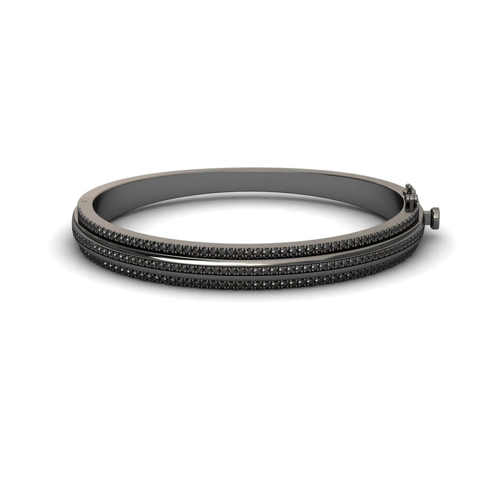 The Bold Black Bangle: Unconventional Elegance - Amalia features a sleek dark metal design with three parallel rows of small black stones and a clasp closure, shown against a white background.