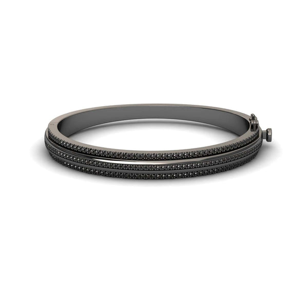 The Bold Black Bangle: Unconventional Elegance - Amalia features a sleek dark metal design with three parallel rows of small black stones and a clasp closure, shown against a white background.