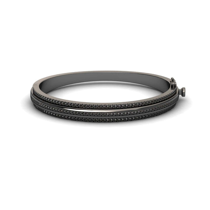 The Bold Black Bangle: Unconventional Elegance - Amalia features a sleek dark metal design with three parallel rows of small black stones and a clasp closure, shown against a white background.