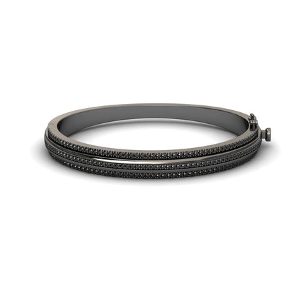 The Bold Black Bangle: Unconventional Elegance - Amalia features a sleek dark metal design with three parallel rows of small black stones and a clasp closure, shown against a white background.