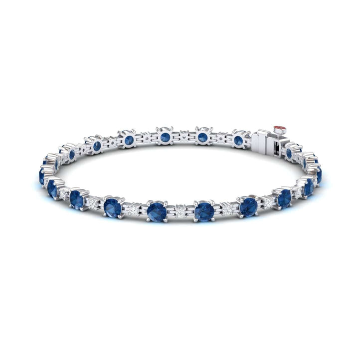 The London Blue Topaz & Diamond Tennis Bracelet - Natalia features round blue gemstones in prong settings, shown on a white background.