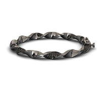 The Black Diamond Twisted Bangle Bracelet - Dakota features a sleek metallic design with embedded dark stones, a twisted motif, and a secure clasp for an elegant, modern look.
