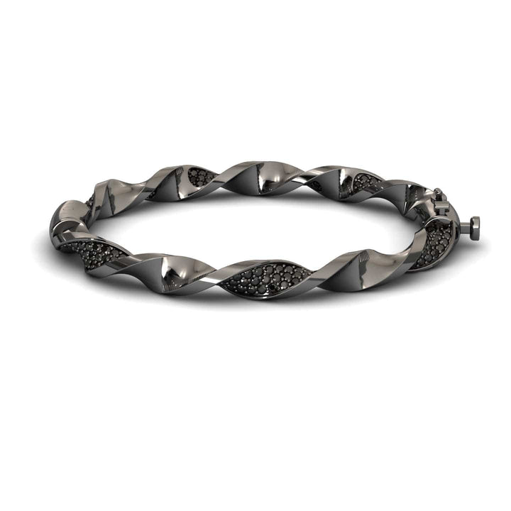 The Black Diamond Twisted Bangle Bracelet - Dakota features a sleek metallic design with embedded dark stones, a twisted motif, and a secure clasp for an elegant, modern look.
