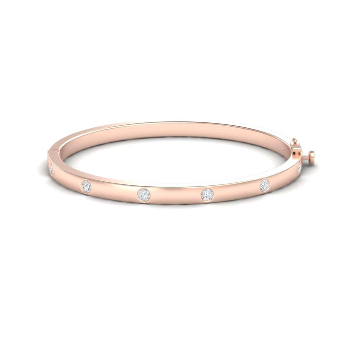 The Diamond Bezel-Set Bracelet - Flavia is a rose gold bangle adorned with evenly spaced round diamonds along its polished surface, showcased on a white background.