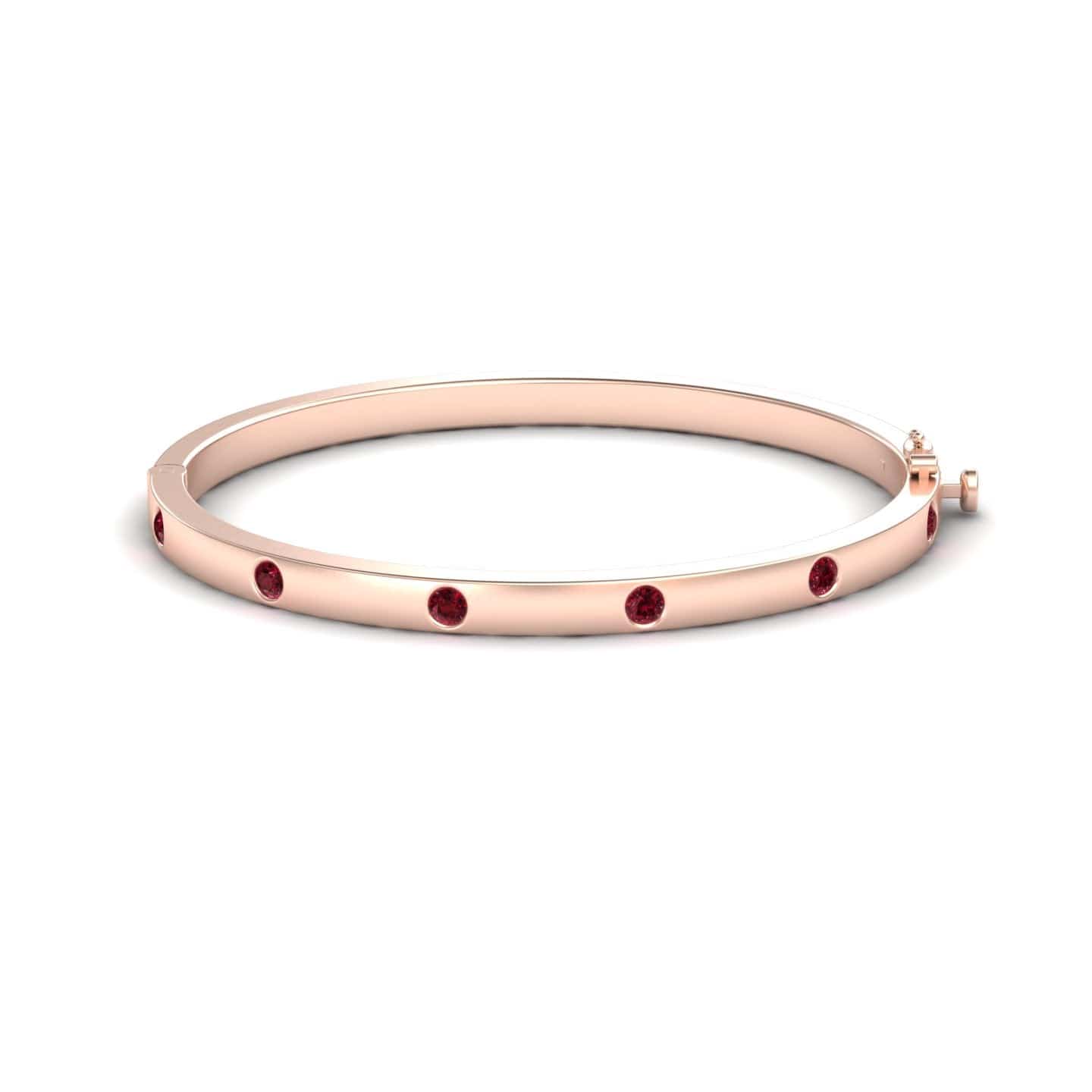 The RUBY Bezel-Set Bracelet - Flavia is a rose gold bangle with evenly spaced round ruby gemstones bezel-set around the outer surface, shown on a white background.