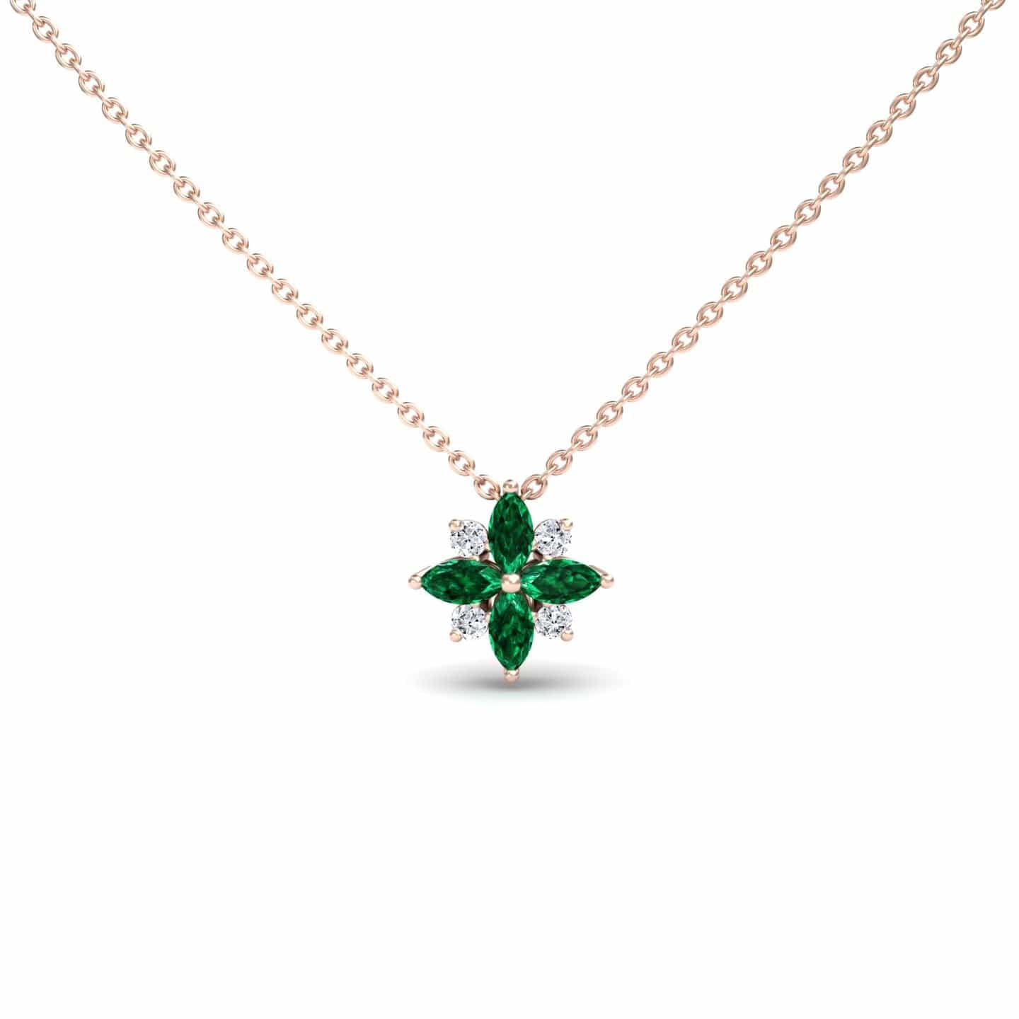 The Emerald & Diamond Flower Necklace - Keira features a gold chain and a flower-shaped pendant with alternating marquise-cut green emeralds and round white diamonds.