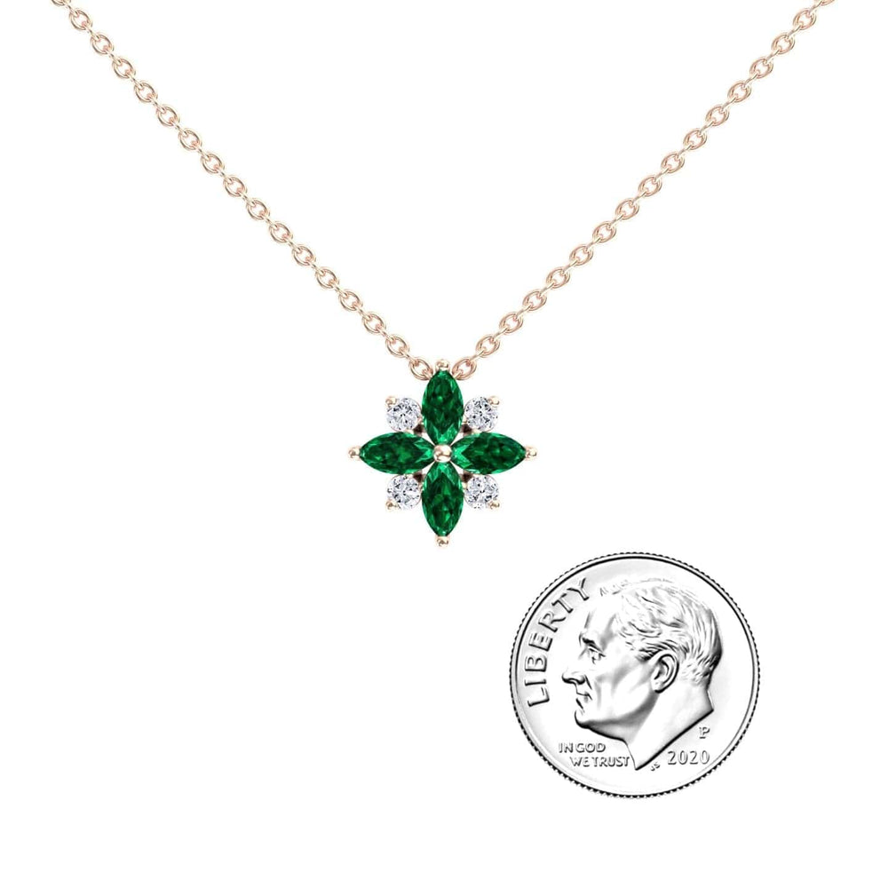 The Emerald & Diamond Flower Necklace - Keira features a gold chain with a floral pendant set with alternating green and clear stones, shown beside a 2020 U.S. dime for scale.
