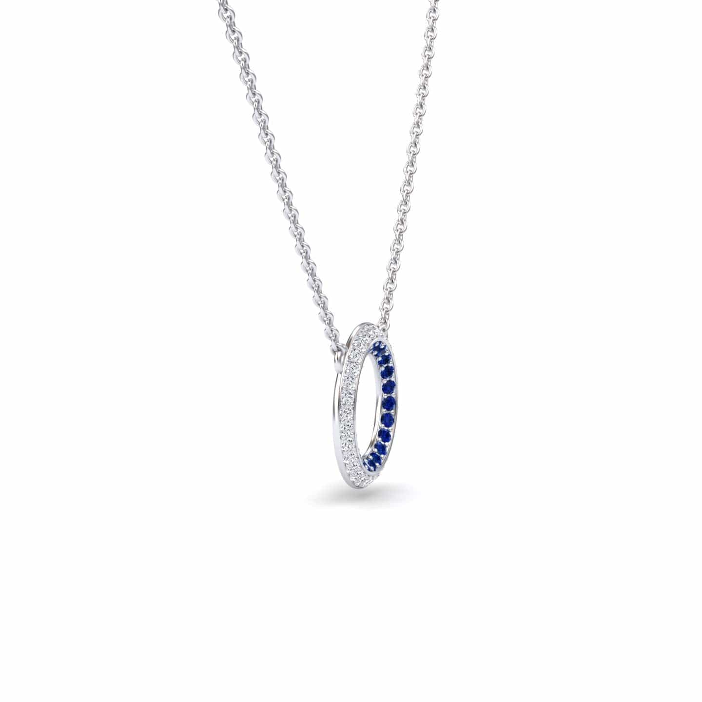 The Blue Sapphire & Diamond Double Halo Circle Necklace - Mona showcases a circular pendant with blue sapphires and diamonds on a delicate chain, displayed against a white background.