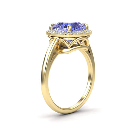 The Tanzanite & Diamond Halo Ring - Ziva features a large oval blue tanzanite at the center, encircled by sparkling diamonds and set in gold with an elegant openwork design beneath the gemstone setting.