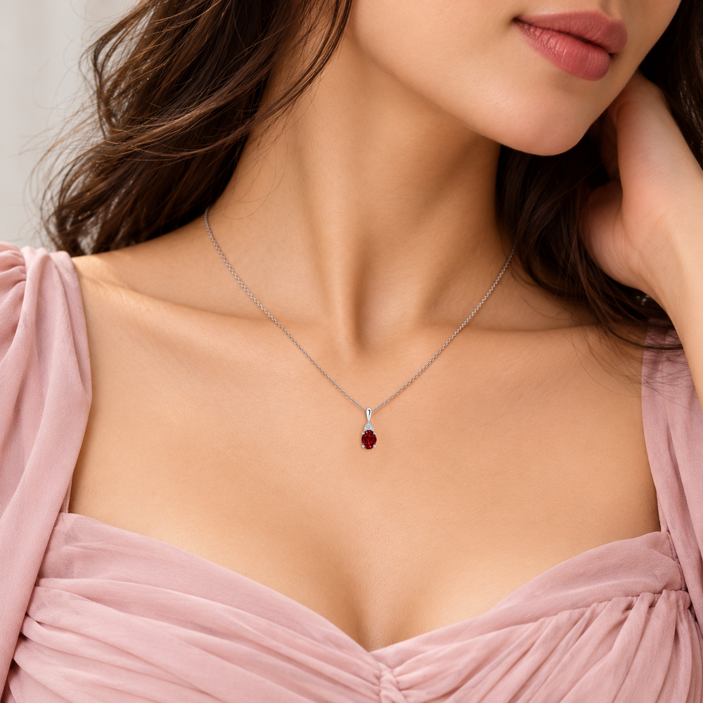 Lab-grown ruby and trio diamond oval solitaire necklace in 14k white gold, worn on model