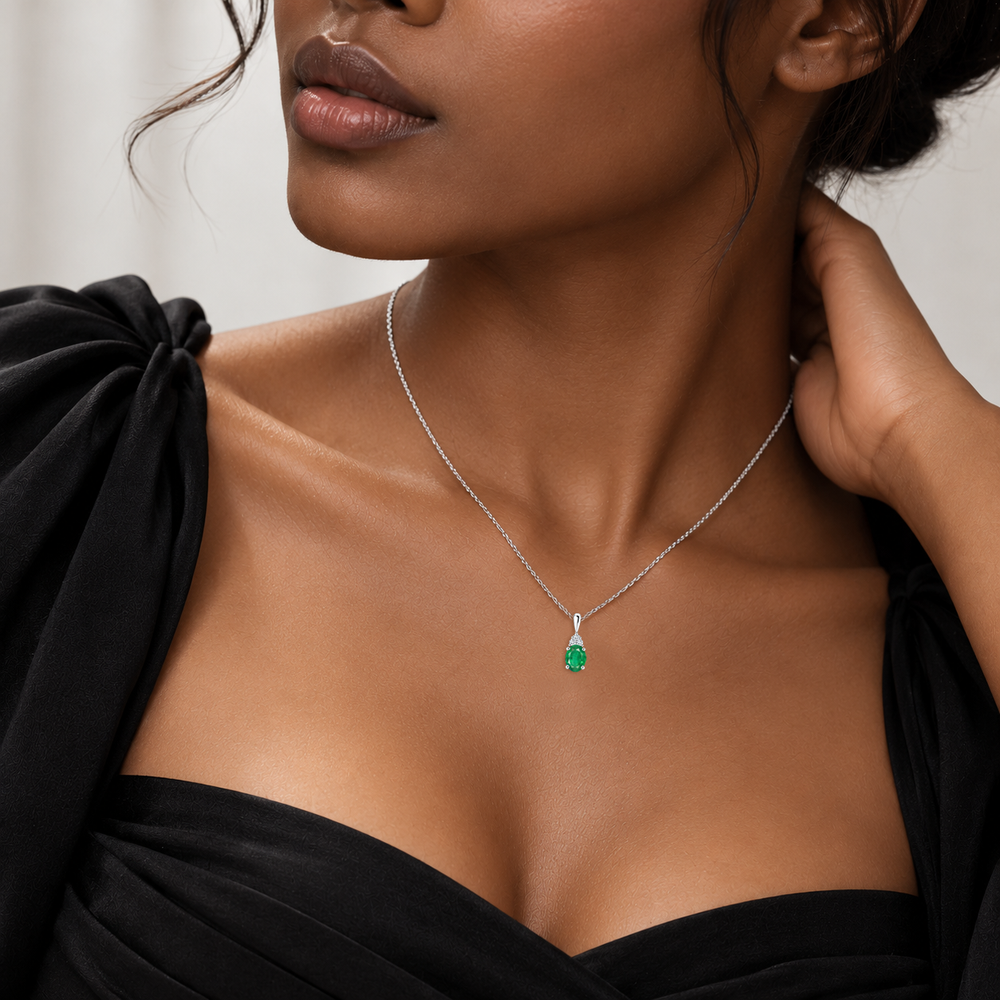 Emerald and trio diamond oval solitaire necklace in 14k white gold, worn on model