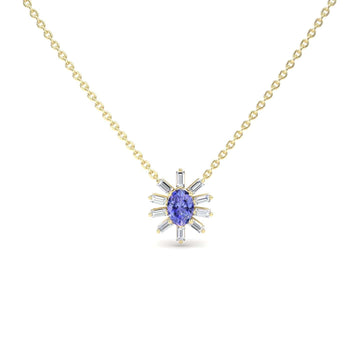 The Tanzanite & Diamond Starburst Necklace - Laura features a gold chain with a central oval blue gemstone and radiating baguette-cut clear stones in a starburst design, displayed against a white background.
