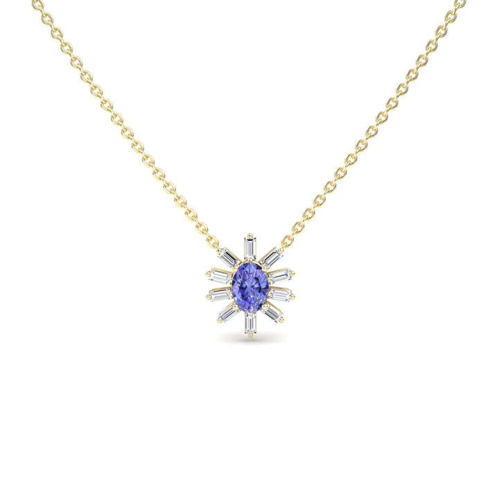 The Tanzanite & Diamond Starburst Necklace - Laura features a gold chain with a central oval blue gemstone and radiating baguette-cut clear stones in a starburst design, displayed against a white background.