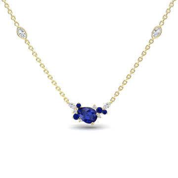 The Blue Sapphire & Diamond Bouquet Necklace - Daria features a gold chain with a central pear-shaped blue gemstone, accented by small blue and white stones and two marquise-cut white stones along the chain.
