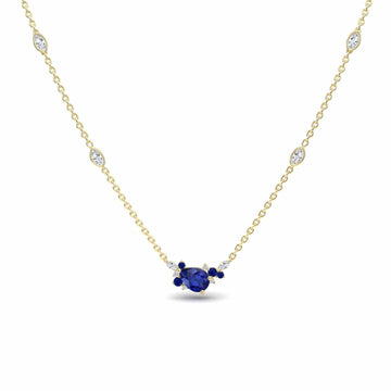 The Blue Sapphire & Diamond Bouquet Necklace - Daria features a central oval blue sapphire flanked by smaller sapphires and diamonds, with additional small diamonds set along its elegant gold chain.