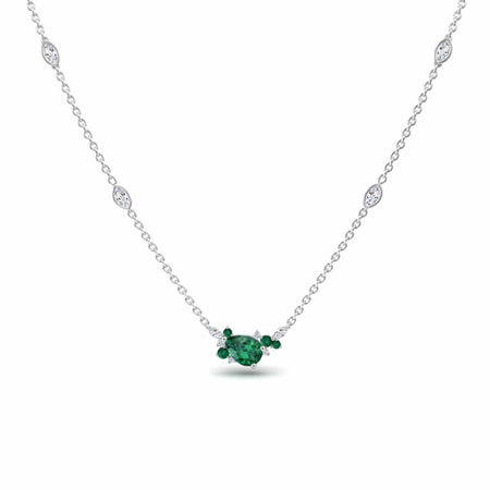 The Emerald & Diamond Bouquet Necklace - Daria is a delicate silver piece with a central oval green gemstone, two smaller side stones, and four small round white gems elegantly spaced along the chain.
