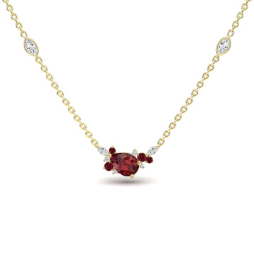 The Ruby & Diamond Bouquet Necklace - Daria features a gold chain with a pear-shaped red centerpiece, small white and red accent stones, and two marquise-cut white stones set along the chain.