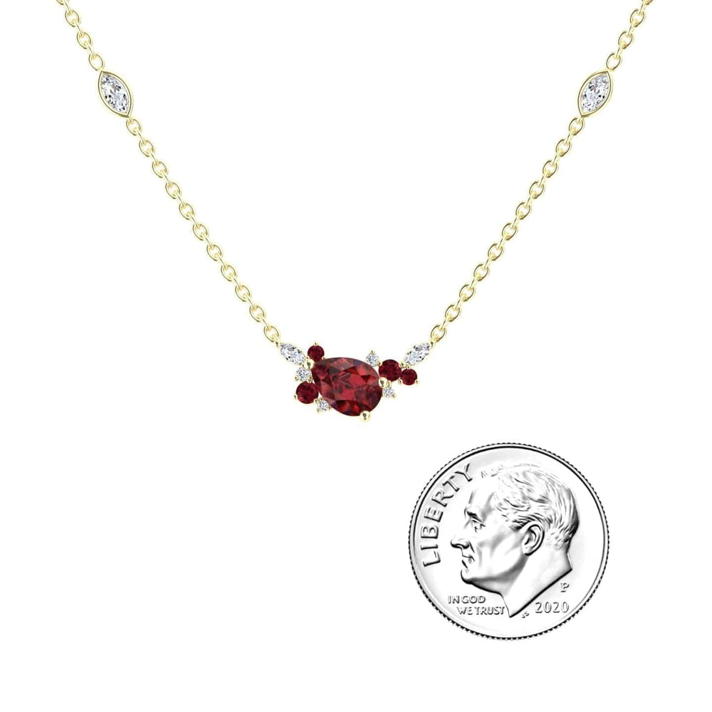 The Ruby & Diamond Bouquet Necklace - Daria features a central oval ruby, flanked by small diamonds and rubies, plus two marquise diamonds on the gold chain. Shown beside a 2020 U.S. dime for size comparison.