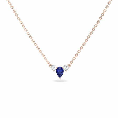 The Blue Sapphire & Diamond Three-Stone Necklace - Jina showcases a teardrop-shaped blue sapphire pendant flanked by two round diamonds, all set on a delicate gold chain against a white background.
