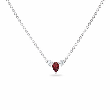The Ruby & Diamond Three-Stone Necklace - Jina features a silver chain with a teardrop-shaped red gemstone pendant, accented by two small clear stones on each side, shown against a white background.