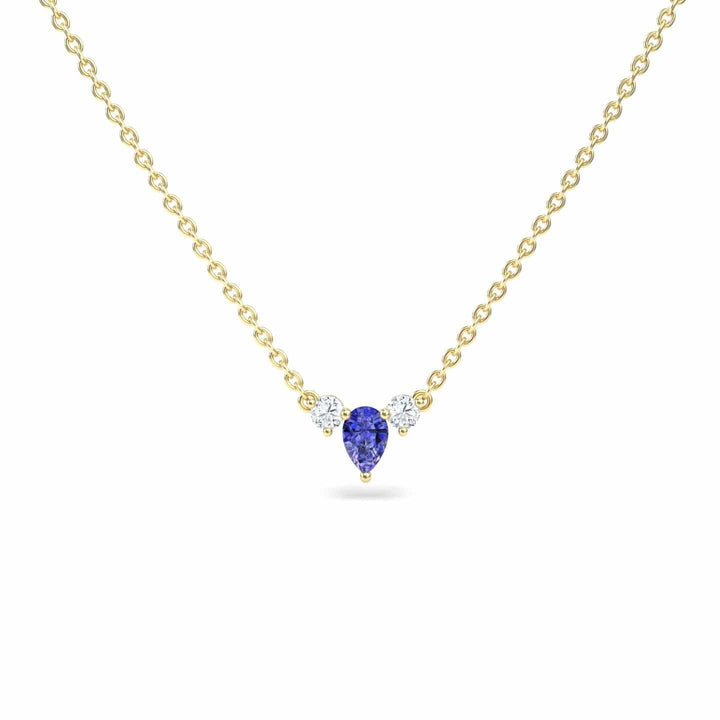 The Tanzanite & Diamond Three-Stone Necklace - Jina showcases a teardrop-shaped blue tanzanite pendant flanked by two round diamonds, all set on a gold chain and displayed against a white background.