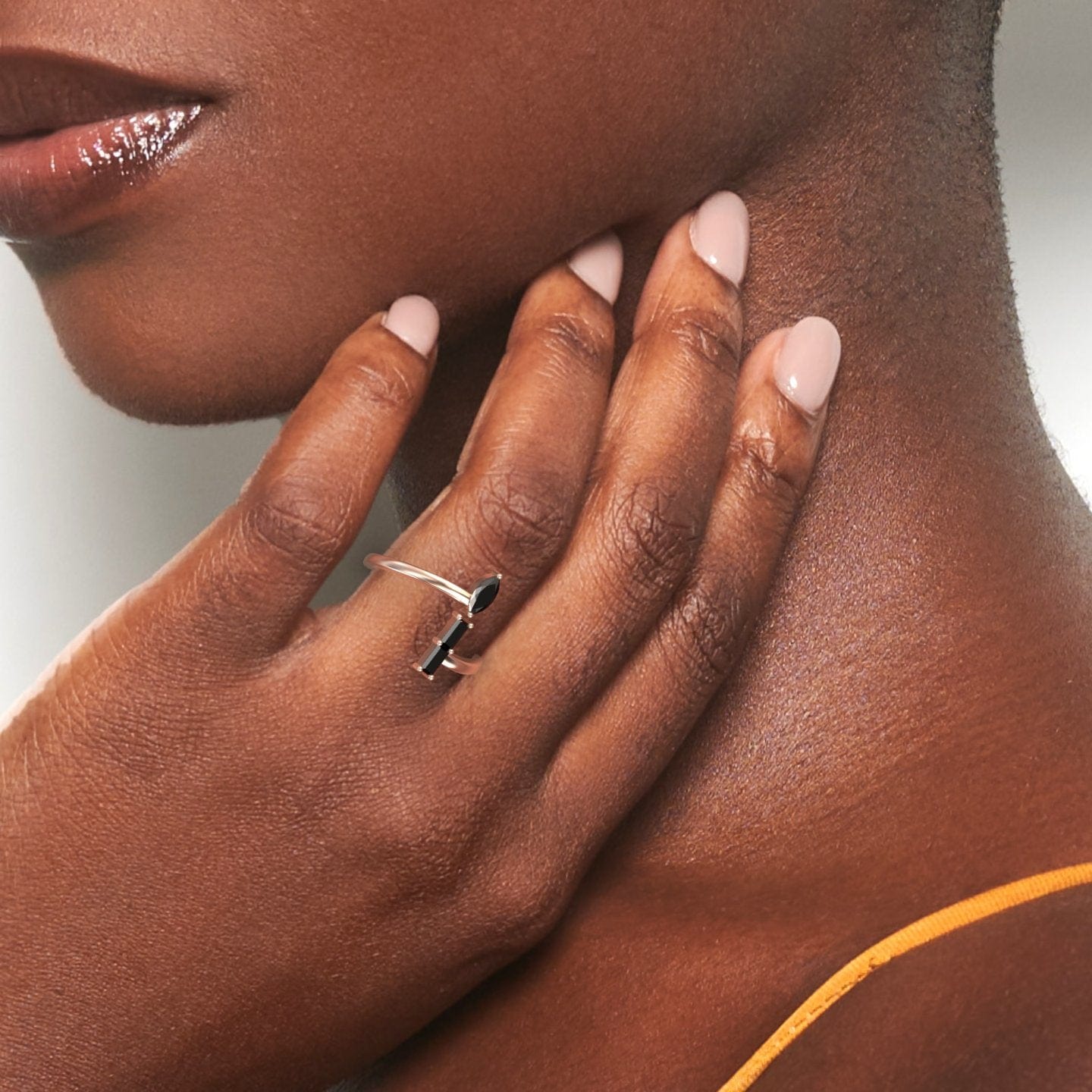 A woman with nude nails gently touches her neck, highlighting the Statement Shimmer: Black diamond’s Mesmerizing Magic – MYSR18 silver ring. She wears a yellow strap top and her glowing skin adds to the ring’s allure.