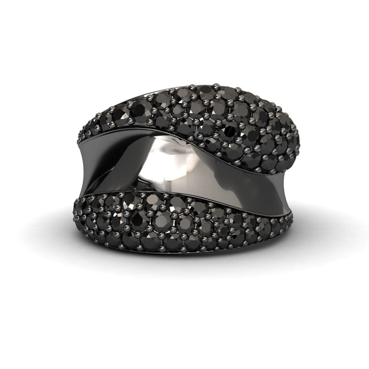 The Black Diamond Sculpted Wave Pave Statement Ring - Kiana features a wide silver band with a central wavy black stripe, bordered by sections paved with sparkling black gemstones, set against a white background.