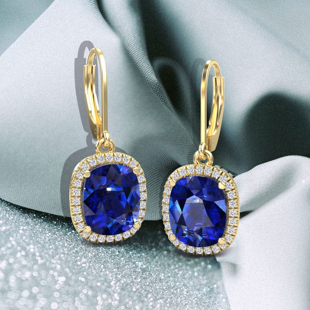 Gold earrings with sapphire gemstones on a soft fabric background