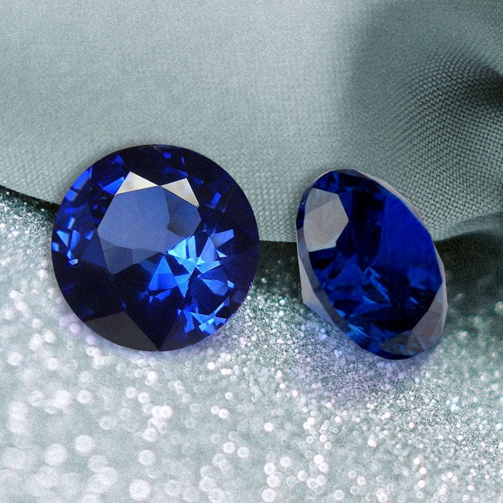 Two blue sapphire gemstones on a textured gray background