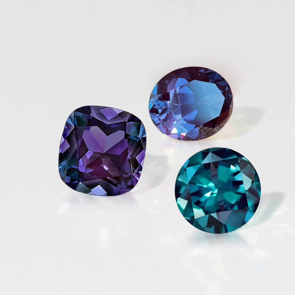 Three alexandrite gemstones on a light gray background